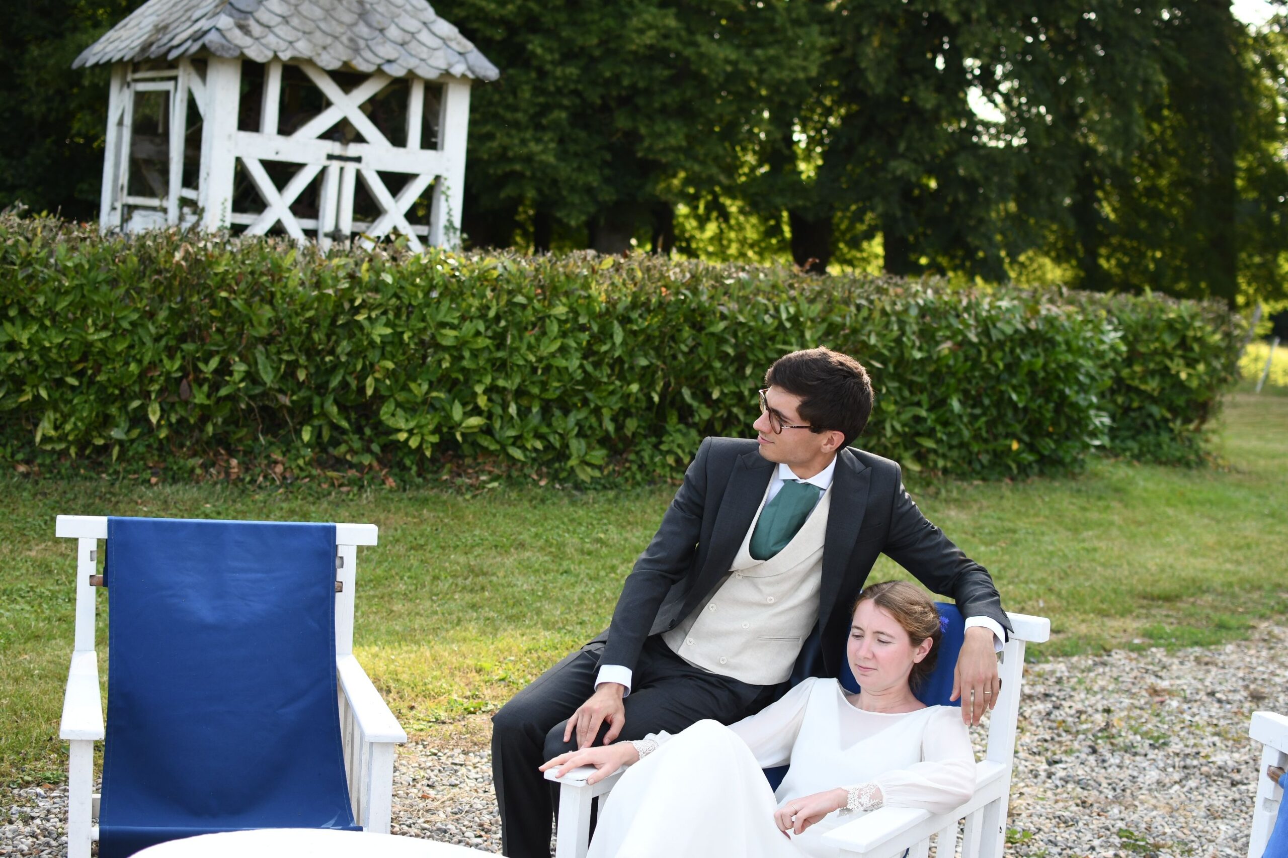 Mariés détendus sur des fauteuils blancs dans le parc du Château de Lihus