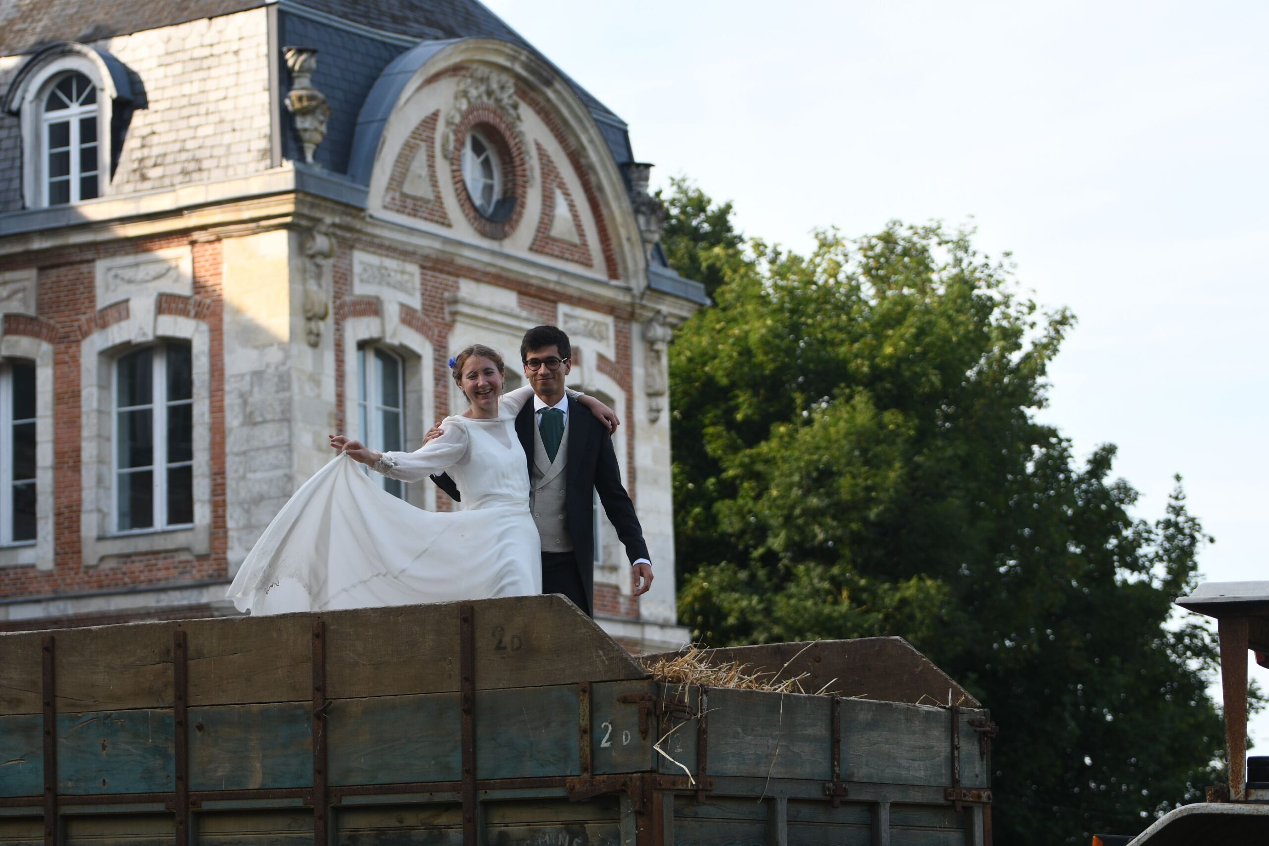 Mariée soulevant sa robe sur la remorque, façade du Château de Lihus en fond